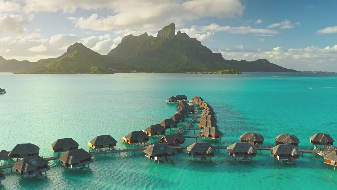 Aerial view of overwater bungalows in Bora Bora with Mount Otemanu in the background