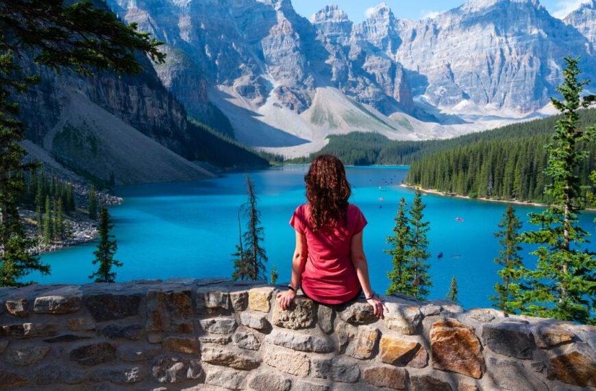 Tourist girl sitting in front of the Moraine Lake in Canada