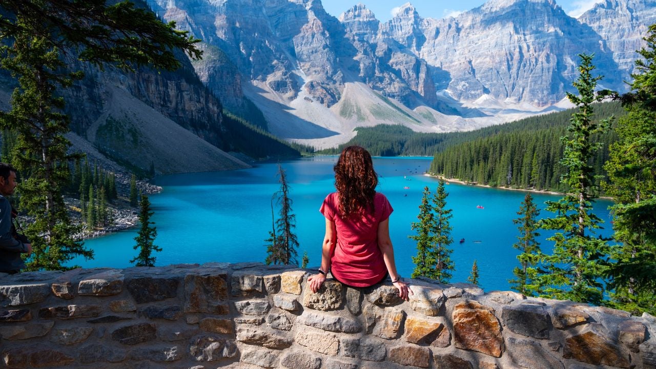 Tourist girl sitting in front of the Moraine Lake in Canada