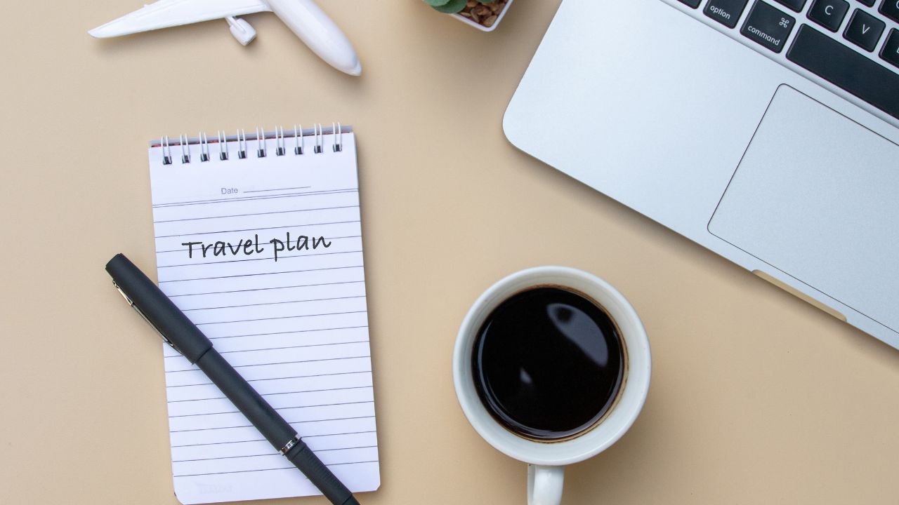 Travel planning desk with a note, airplane miniature, and coffee