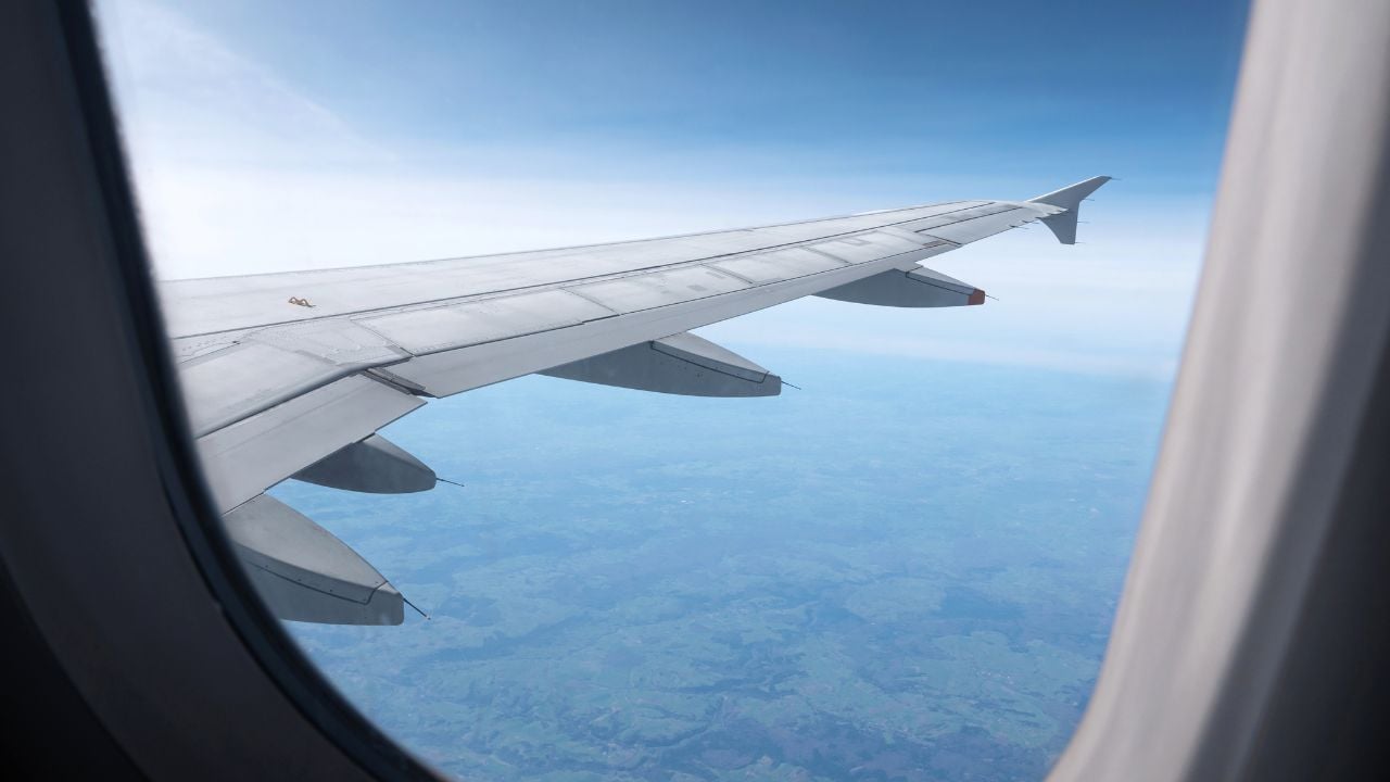 Airplane wing seen from a passenger window in flight.