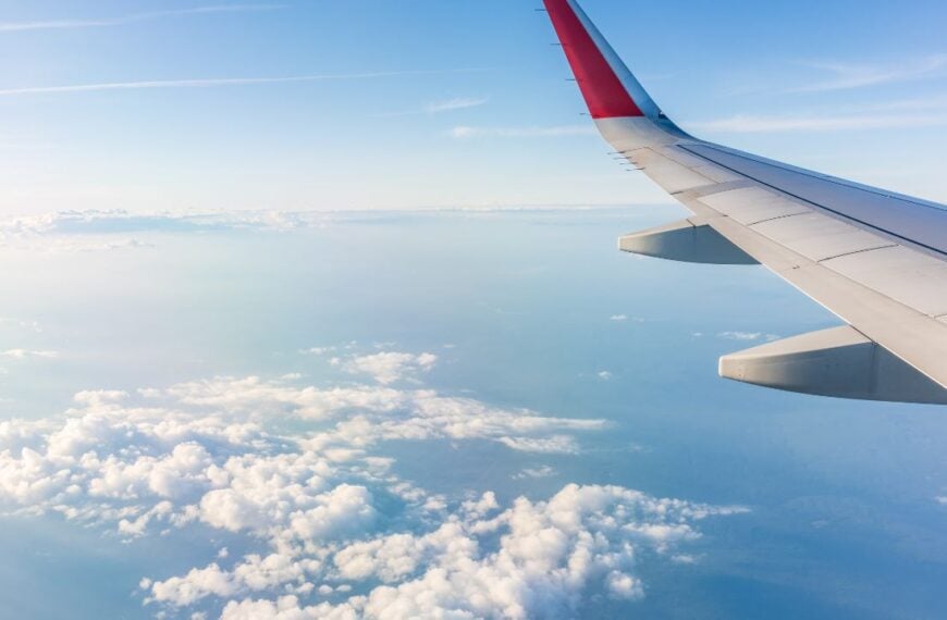 View from the airplane window at a beautiful cloudy sky and the airplane wing. Earth and sky as seen through window of an airplane.
