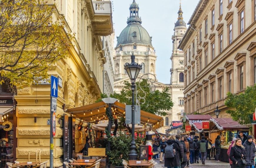 Tourists and locals walk along a festive street decorated with seasonal lights toward St. Stephen's Basilica, which anchors the Advent Basilica Christmas Market in Budapest, Hungary, 01.12.2025