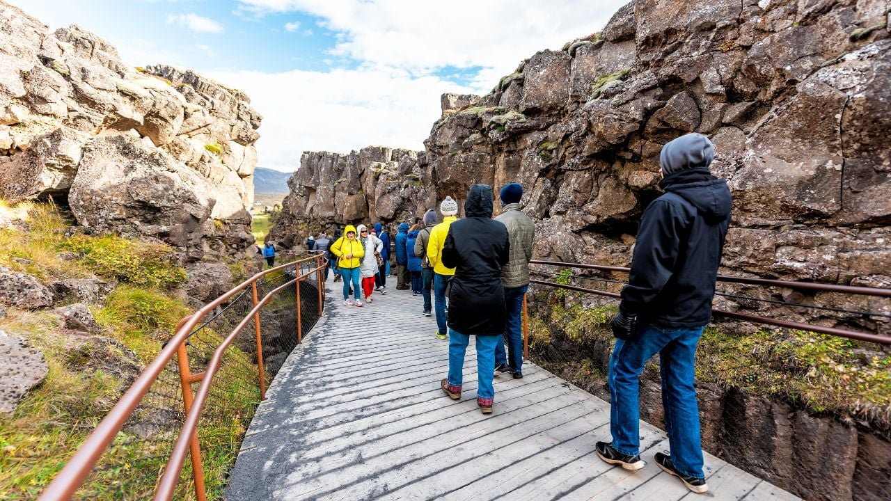 Thingvellir, Iceland - September 20, 2018: National Park people walking on boardwalk trail canyon continental divide plate during day landscape