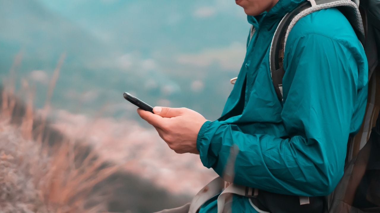 Traveler using a smartphone outdoors in the mountains.