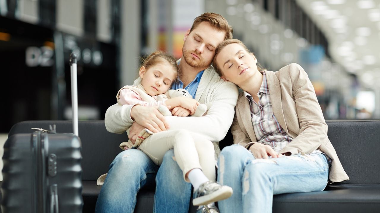 Two young parents and their little daughter napping in airport lounge while waiting for announcement of departure