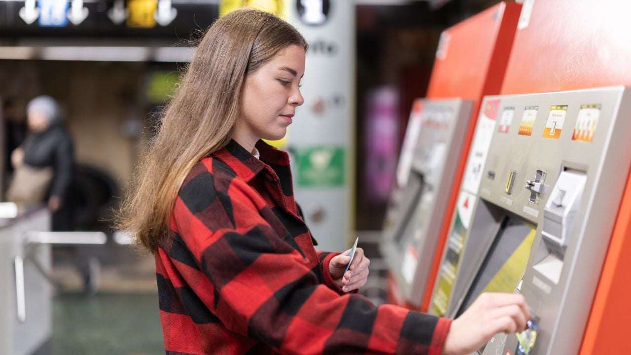 Woman buying a metro pass at a ticket machine.