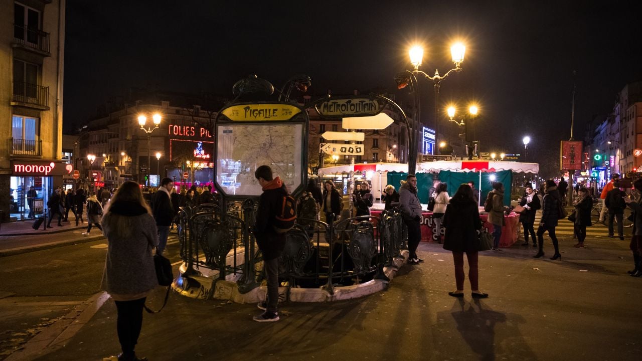 Crowded Paris street near a metro station at night.