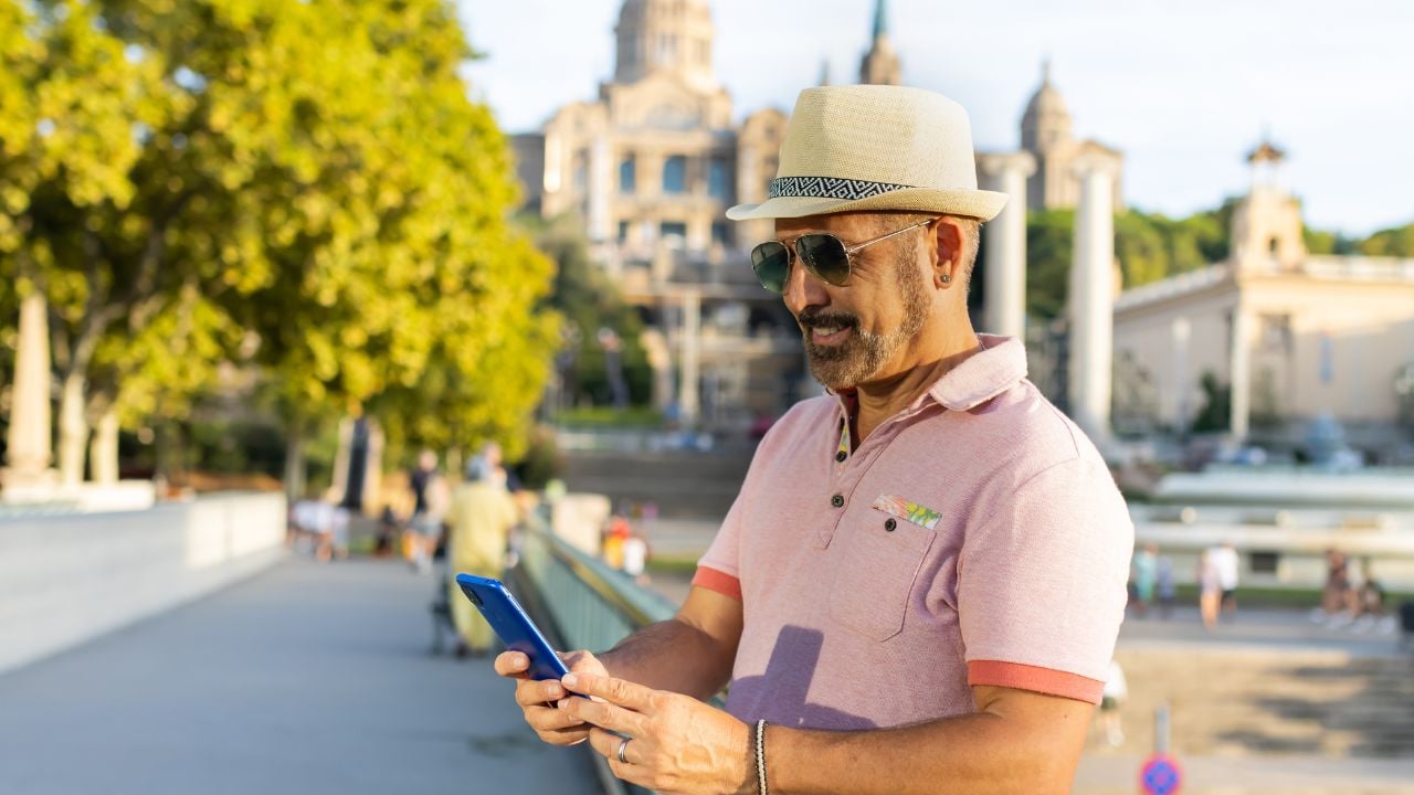 Man with a happy cap checking his cell phone in Montjuic in Barcelona (Spain).