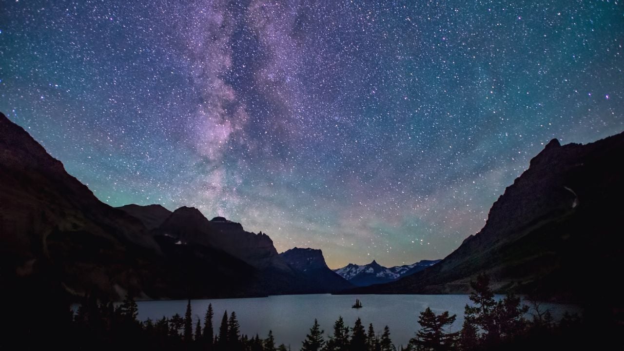The Milky Way stretches across a clear night sky above a quiet mountain lake, capturing the kind of darkness and clarity that make U.S. dark sky parks so memorable for stargazing.
