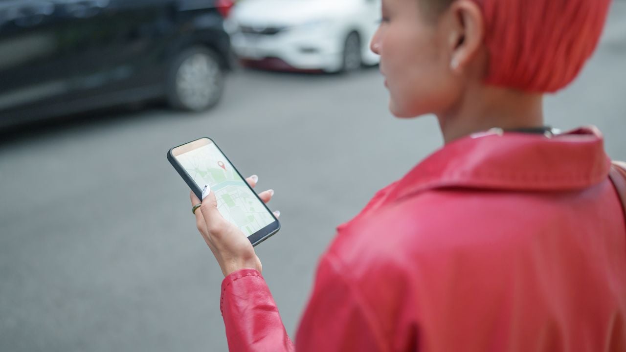 Traveler using a smartphone map application on a city street.