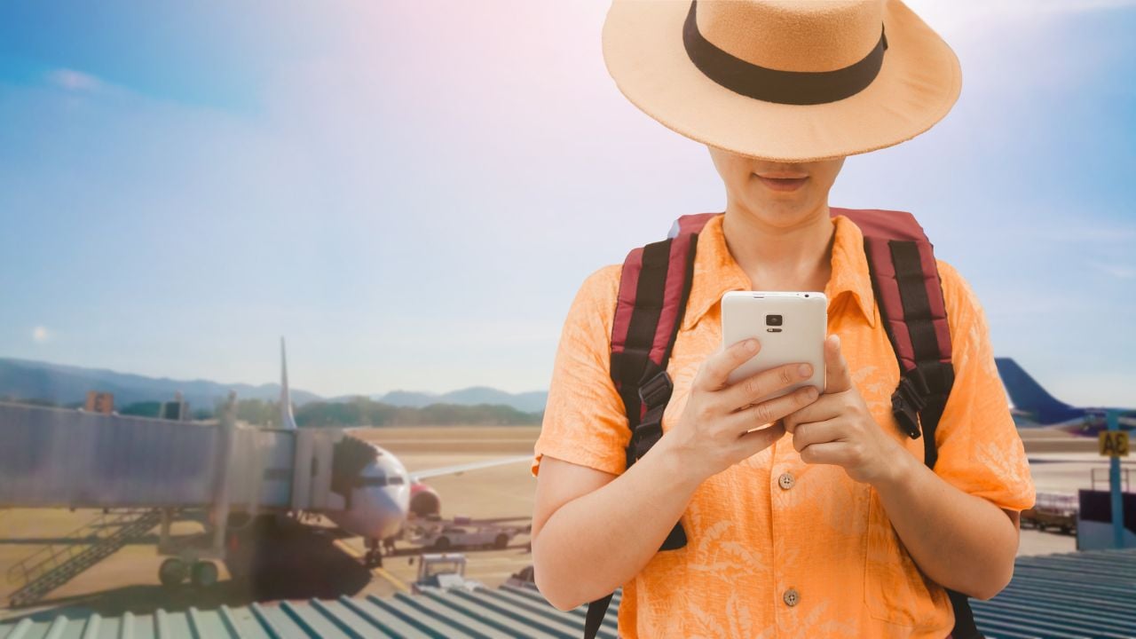 Traveler using a smartphone at an airport.