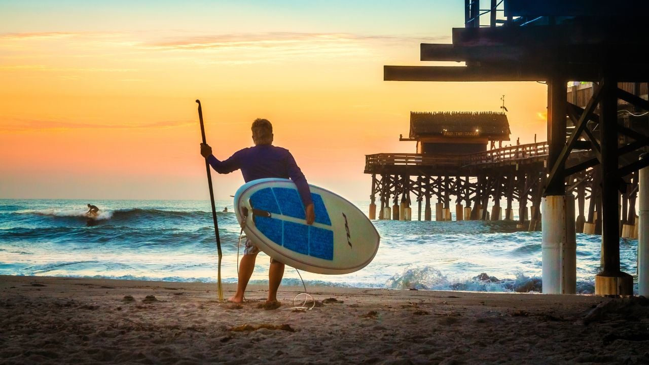 Surfer waiting for waves near Cocoa Beach Pier before dawn.