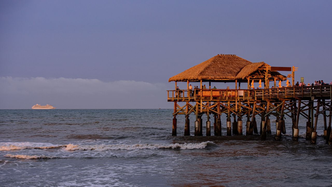 Cocoa Beach Pier at sunset with people walking beside the ocean.