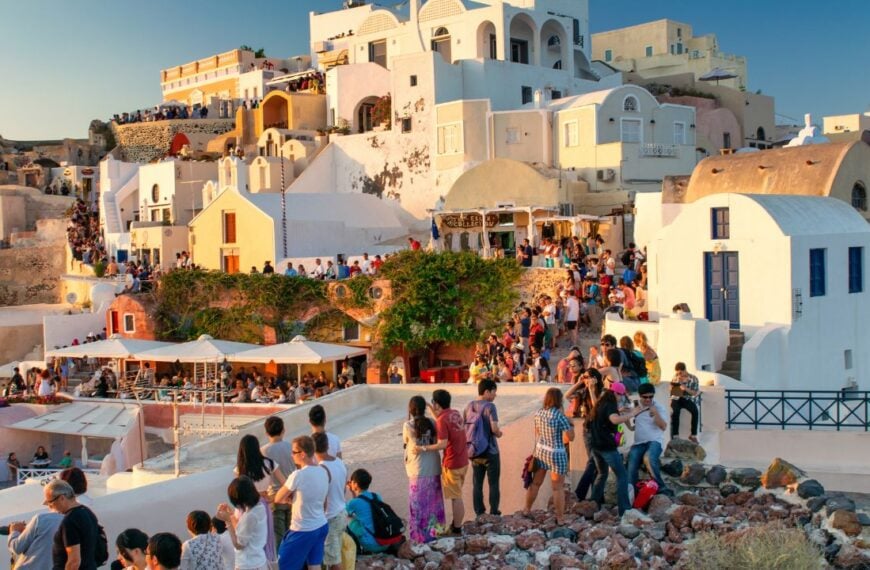 Santorini, Greece - June 11, 2014: Tourists gathered in Oia, Santorini, admiring a breathtaking sunset over the Aegean Sea.