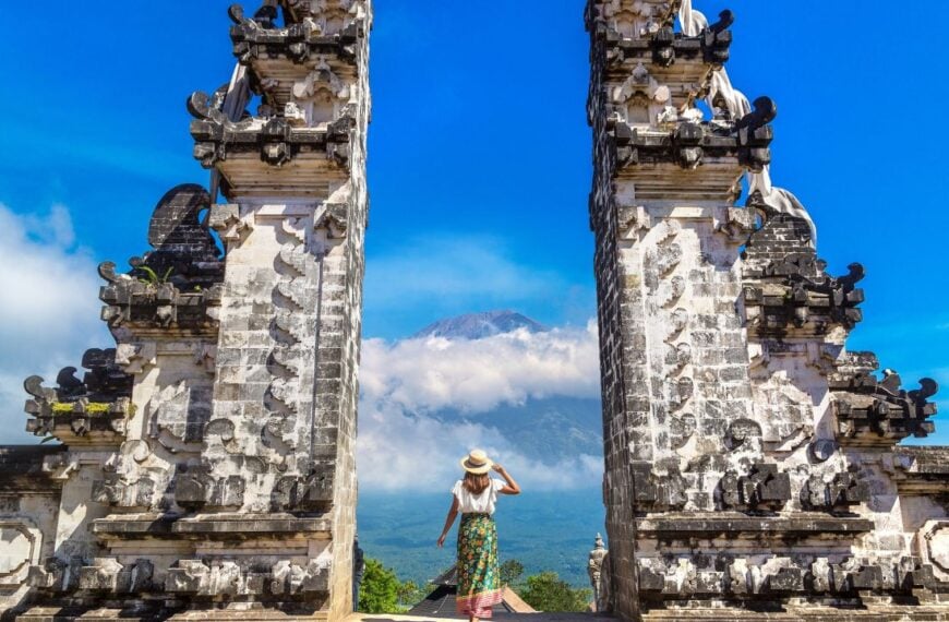 Woman traveler at Ancient gate at Pura Penataran Agung Lempuyang temple and volcano Agung on Bali, Indonesia