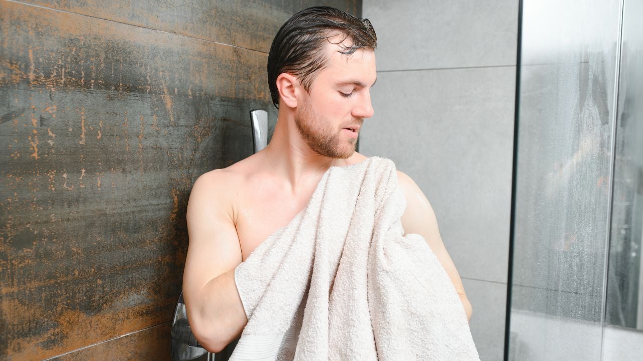 Young man in a bathroom with a towel