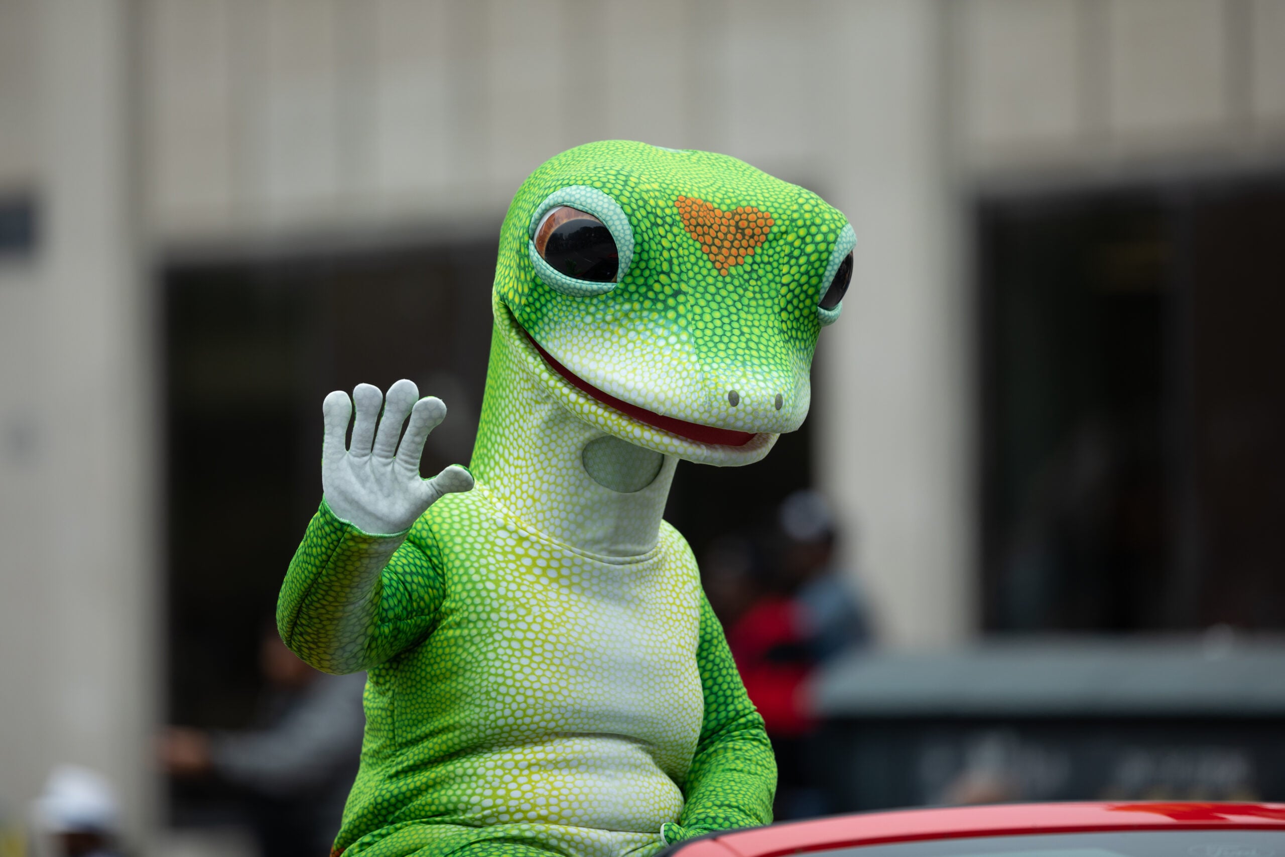 man in geico gecko costume waving