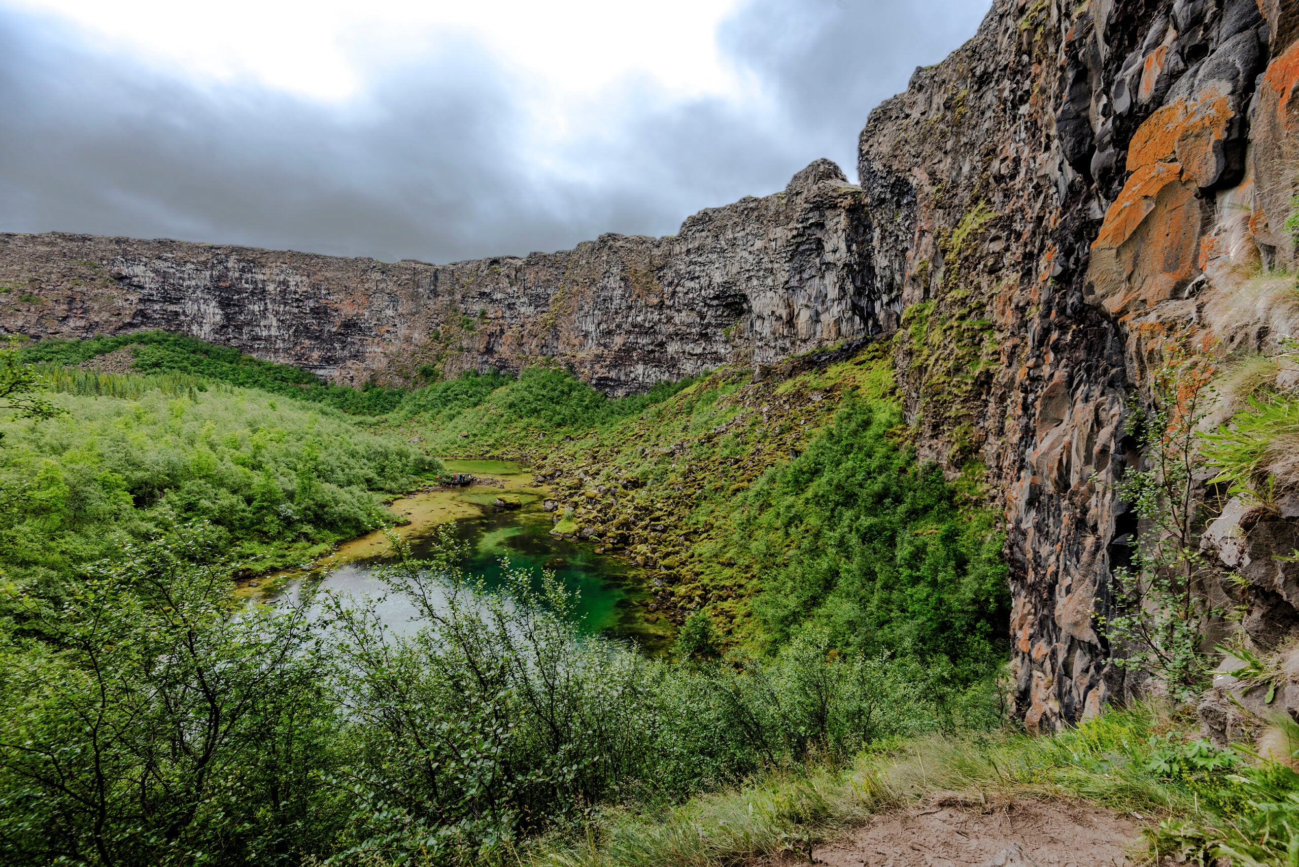 View at Asbyrgi Glacial Canyon in Northern Iceland, Asbyrgisskogur forest and Botnstjorn lake surrounded by steep cliffs.
