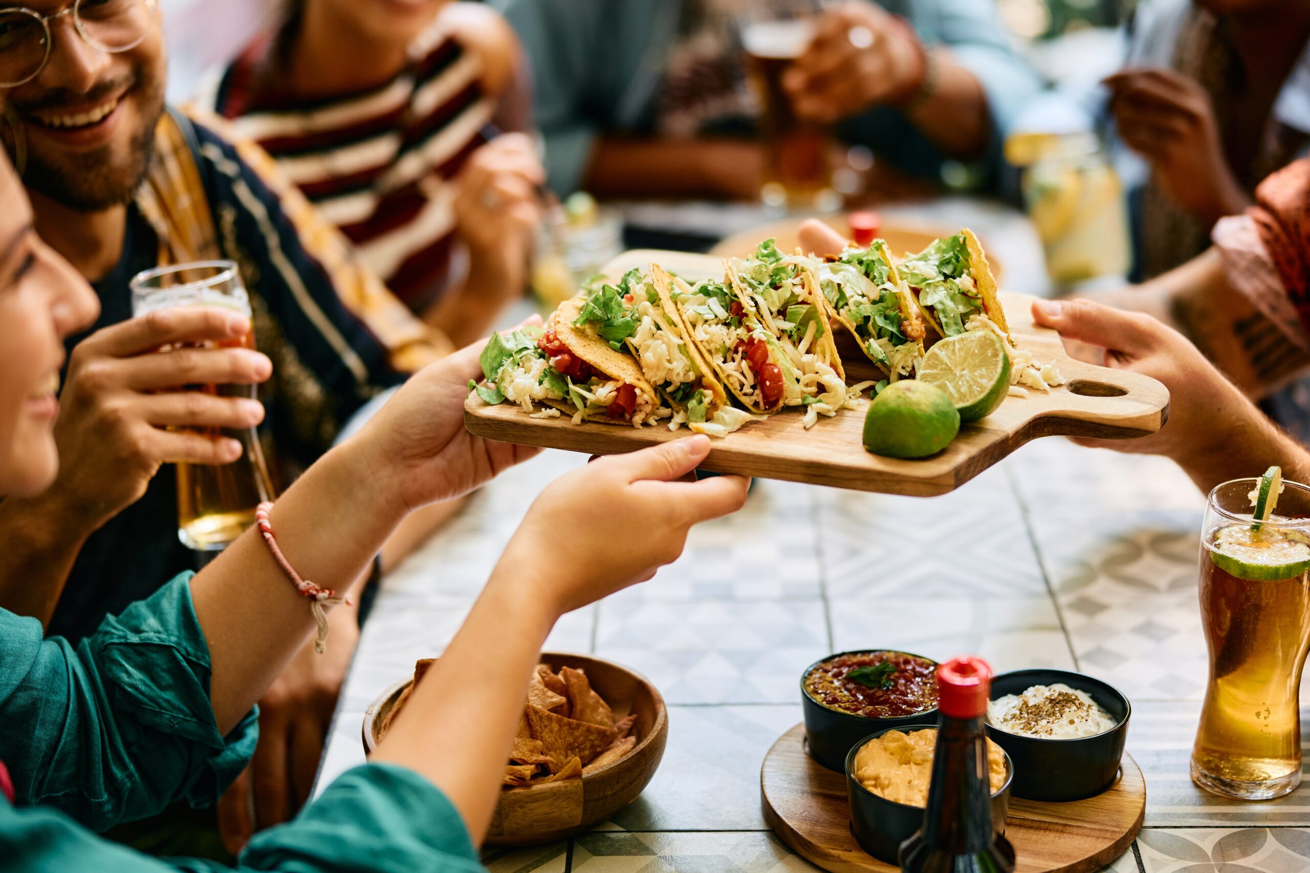Close up of group of friends eating tacos while having lunch together.