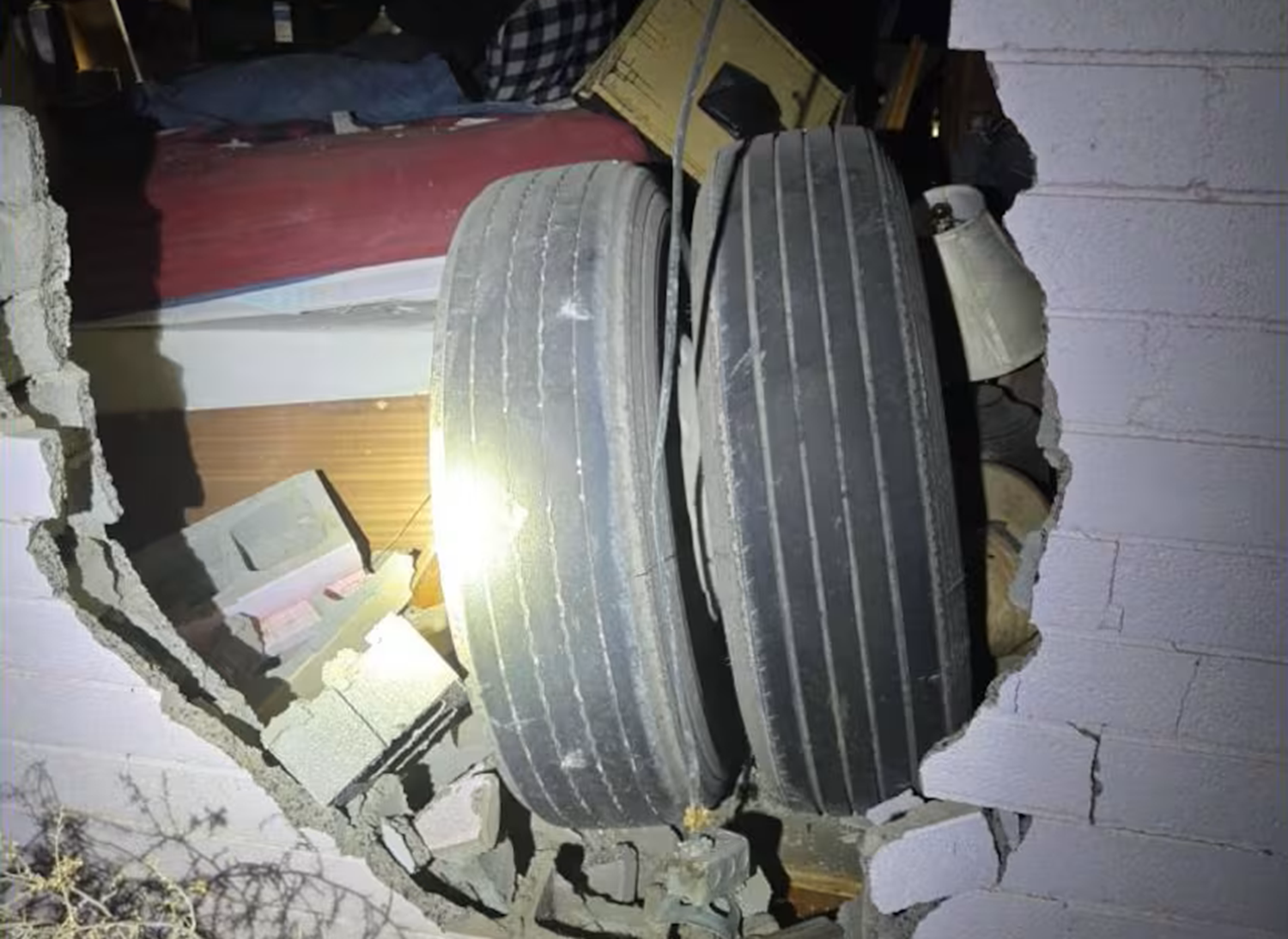 wheel detached from cement truck in bedroom wall