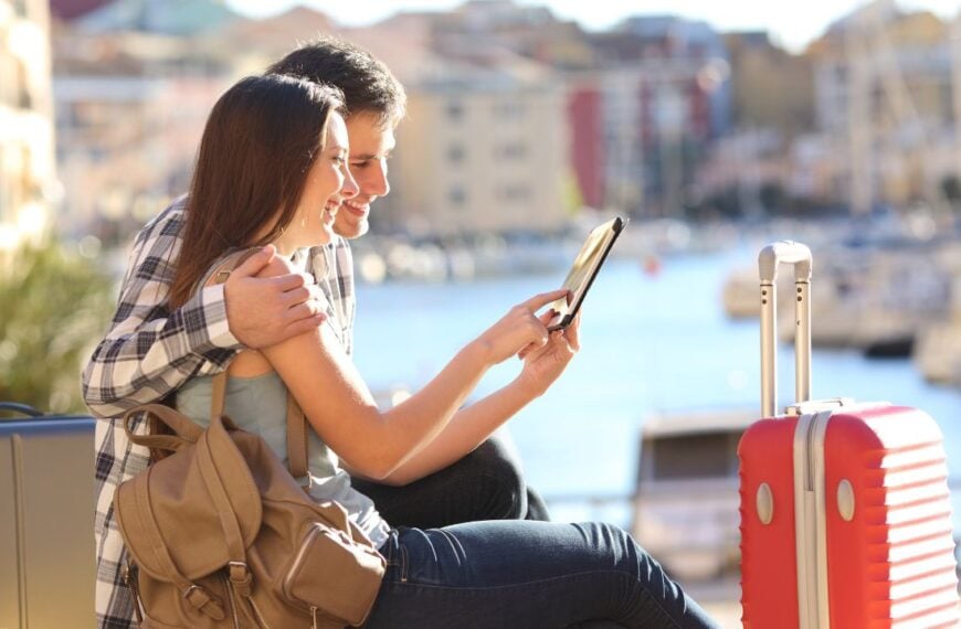 Side view portrait pf a happy couple of tourists consulting a tablet on vacation