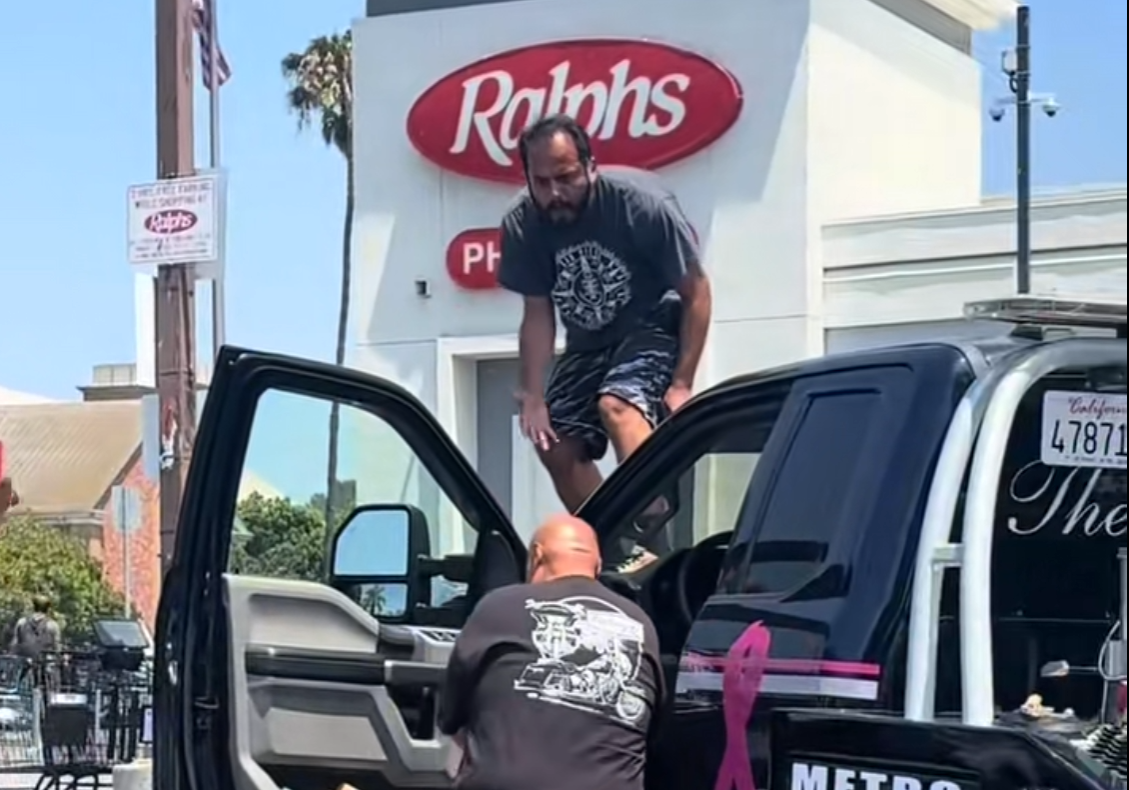 man stands on tow truck and screams at ralphs in la