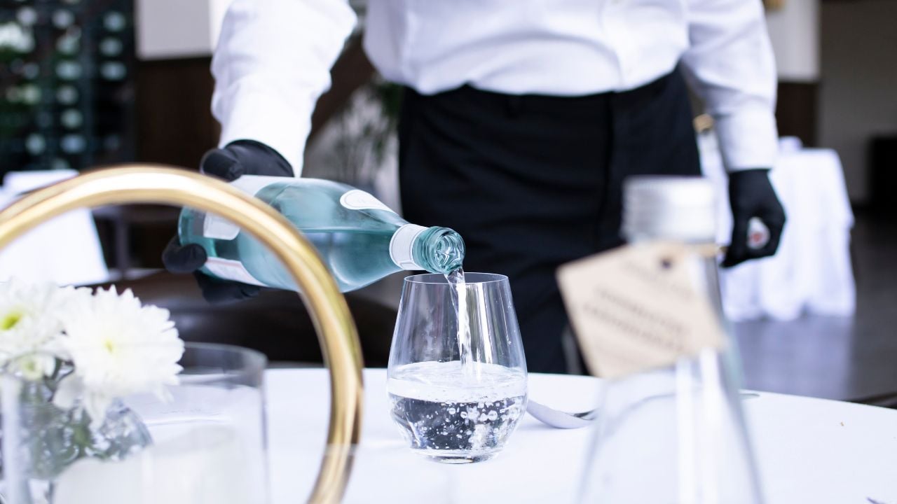 Waiter pouring water into a glass at a restaurant table