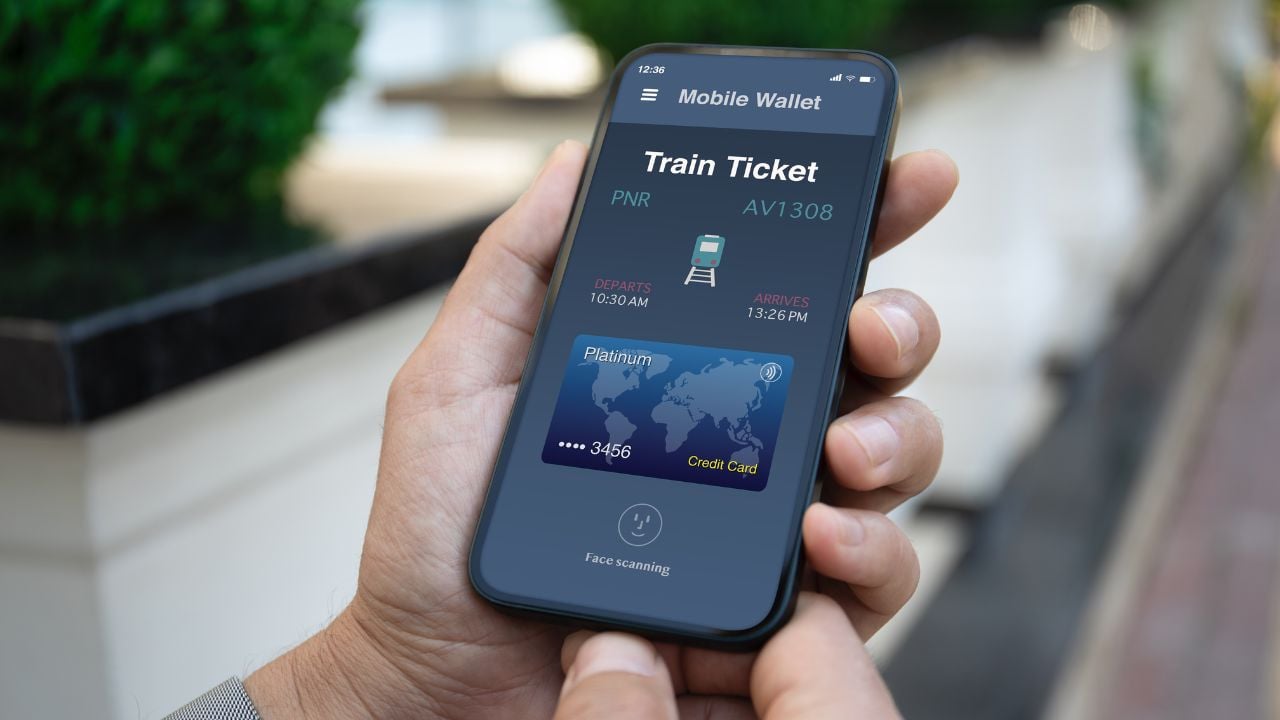 Person holding a phone with a train ticket app at a railway station