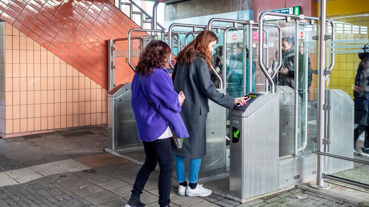 Commuter tapping a phone at a station gate in Amsterdam, Netherlands