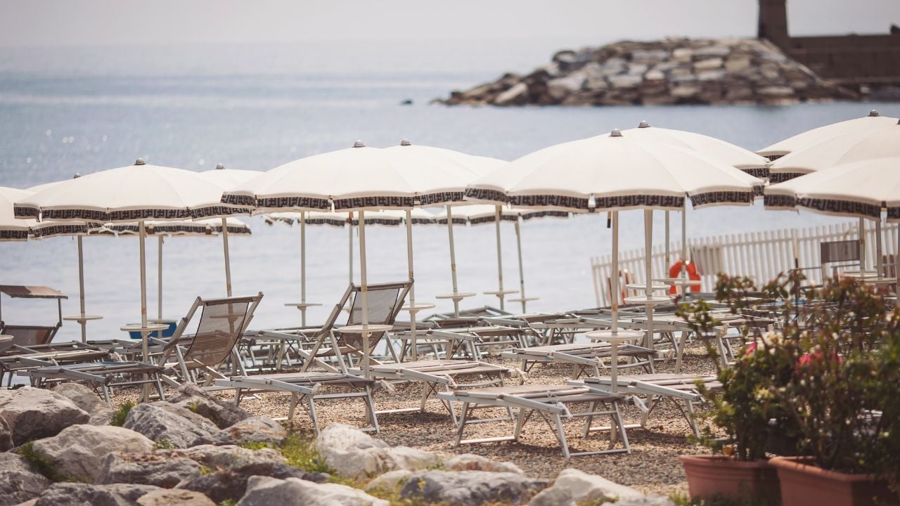 Empty Italian beach with sunbeds, umbrellas, mountains, and the Mediterranean coast