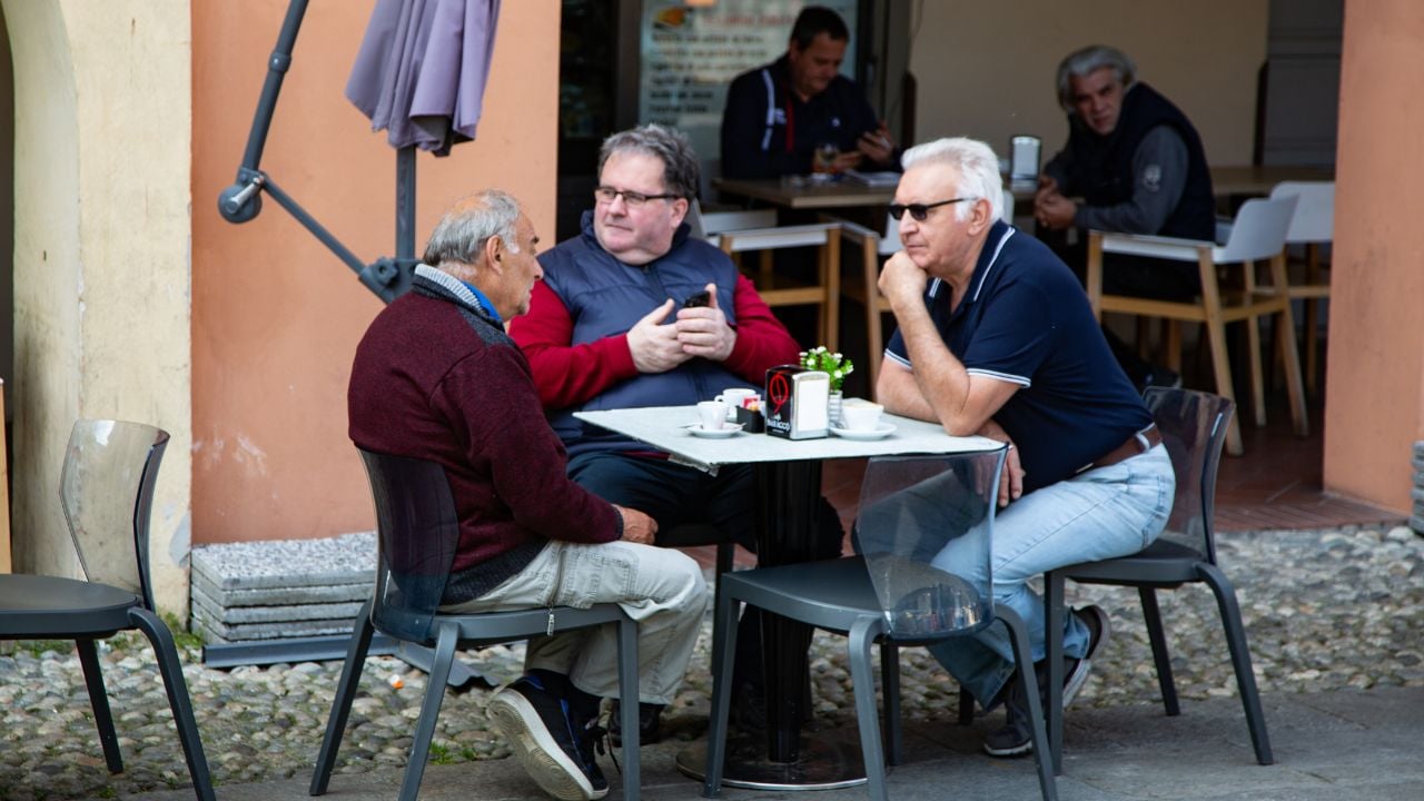 People enjoying coffee and conversation at a traditional Italian bar in Parma, Italy