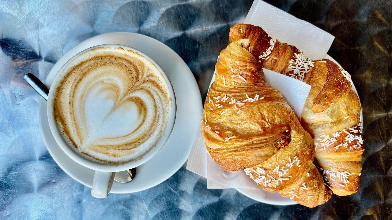 Italian cappuccino with a croissant on a metal table