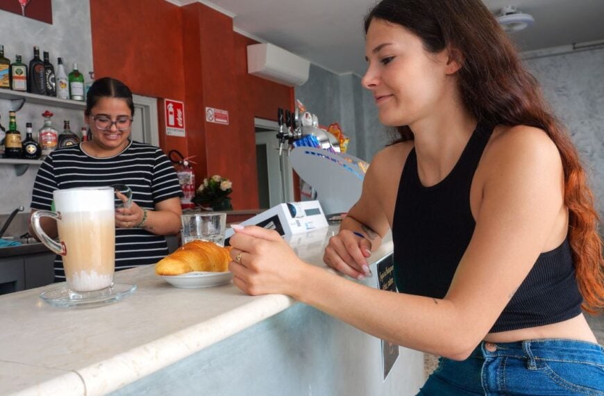 Cremona, Italy - July 5th 2025 A young woman happily orders coffee and a croissant at a local Italian bar with a friendly barista preparing her drink