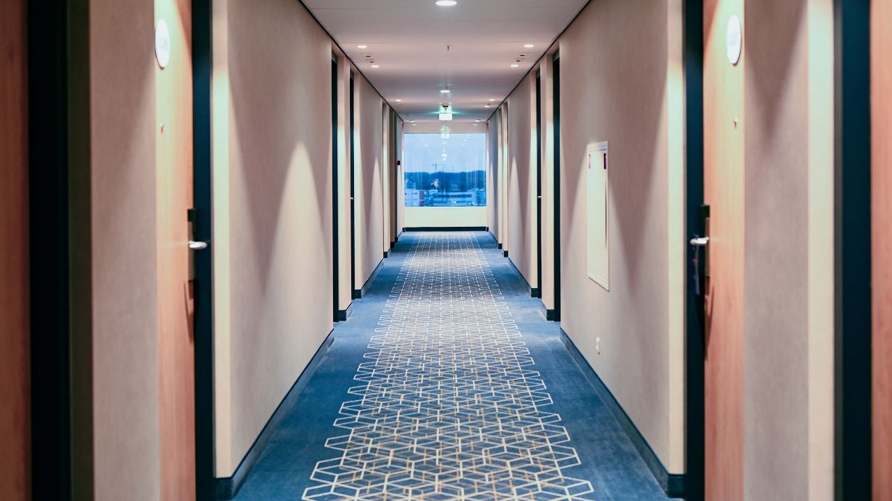 Long hallway with blue carpet and a window