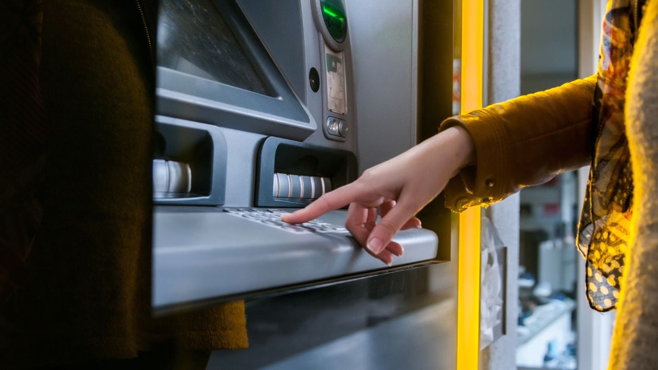 Traveler entering a PIN at an ATM keypad