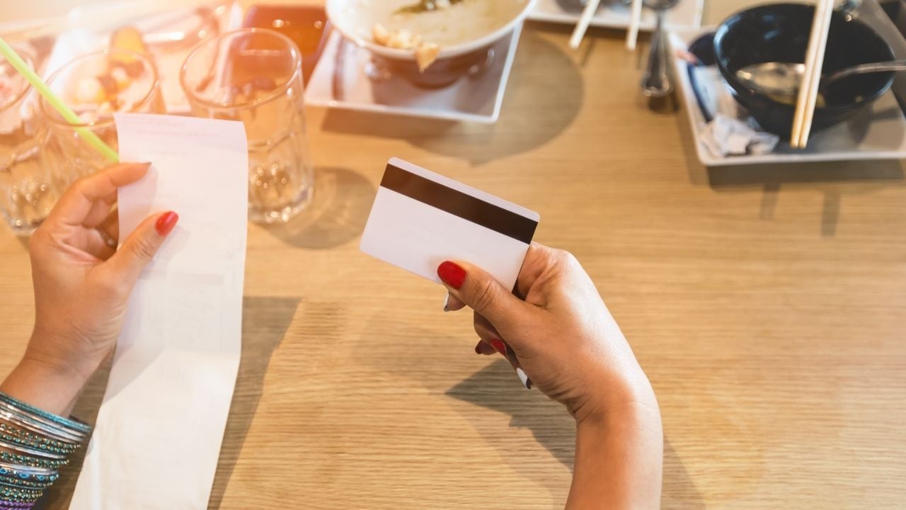 Restaurant customer holding a credit card while checking a bill