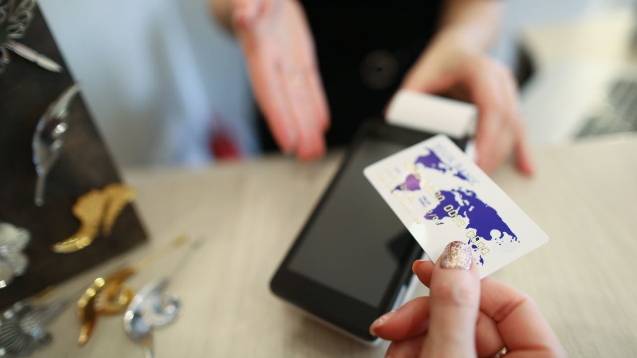 Person holding a credit card near a contactless payment terminal