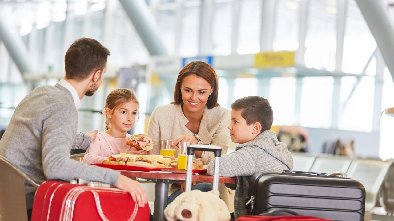 Family eating snacks together in an airport restaurant before departure