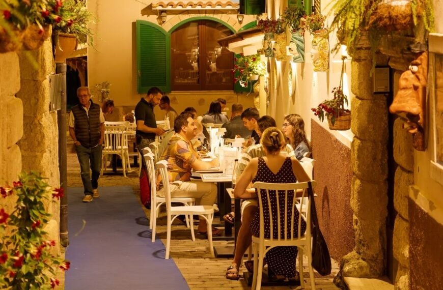 Warm lighting, outdoor tables, and a cozy old-town setting capture the kind of relaxed travel dinner that often becomes the most memorable moment of a trip.