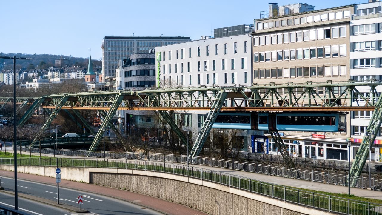 Blue suspended railway train traveling through Wuppertal, Germany