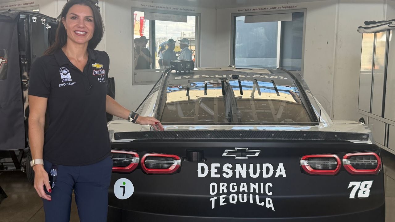 A photo of racing driver Katherine Legge posing with her car in 2025.
