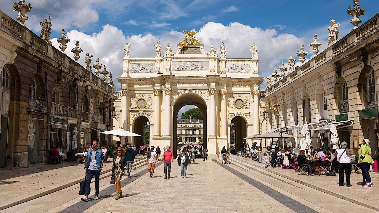 People passing under the Héré Arch near Place Stanislas in Nancy, France