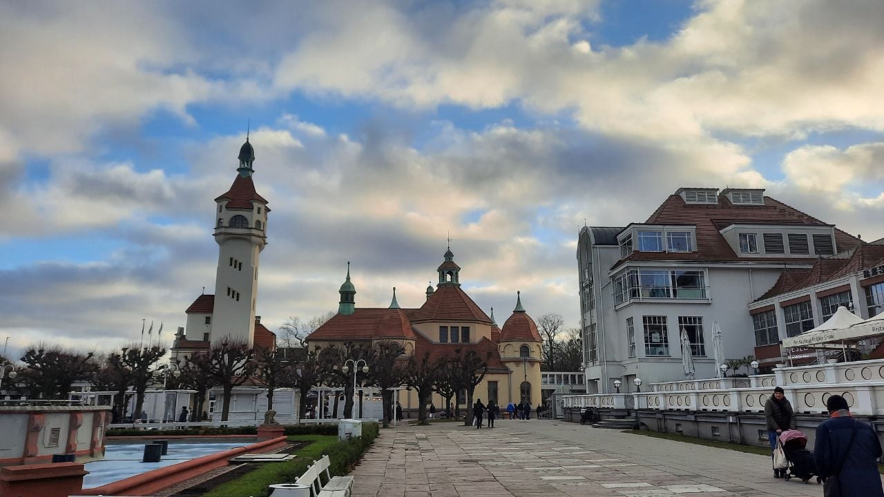 Square in Sopot, Poland, with lighthouse and historic buildings under a cloudy sky