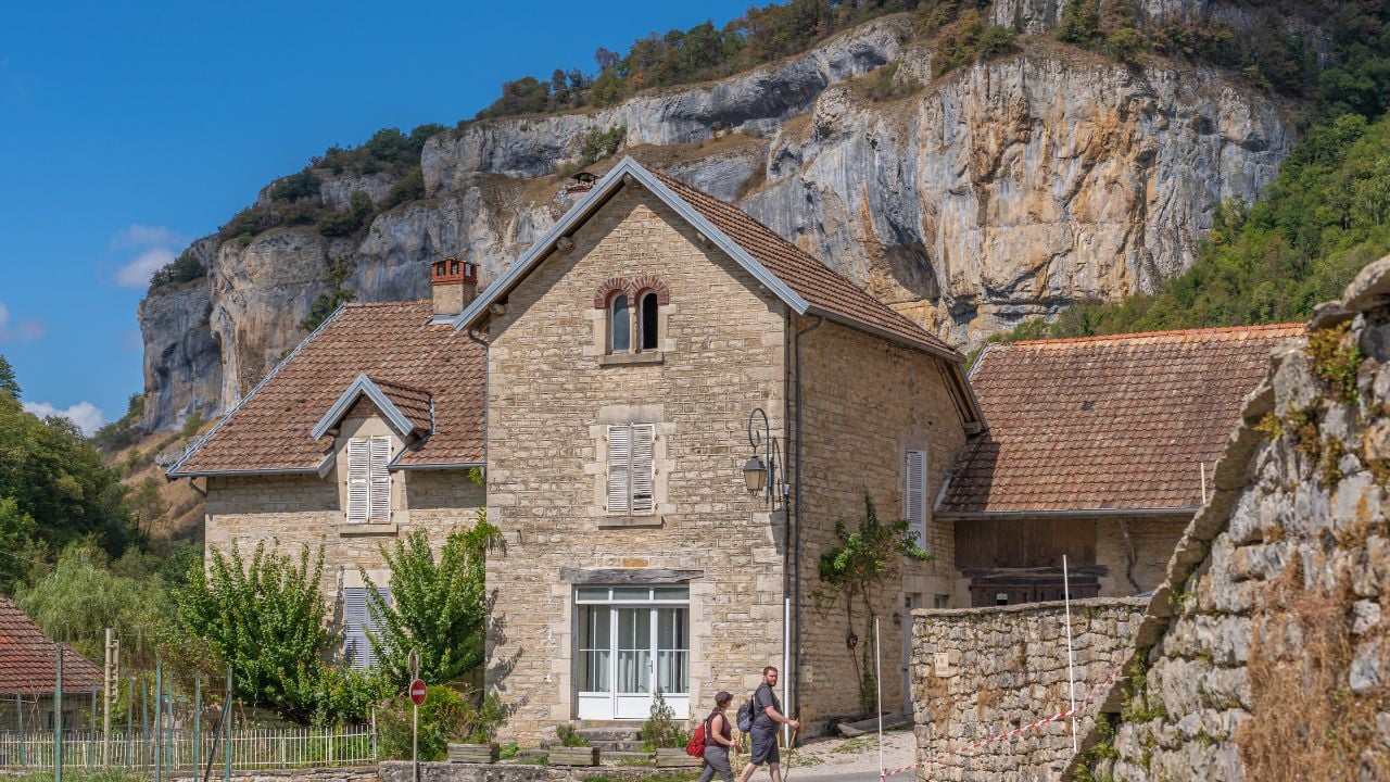 Village of Baume-les-Messieurs with cliffs behind it in the Jura, France