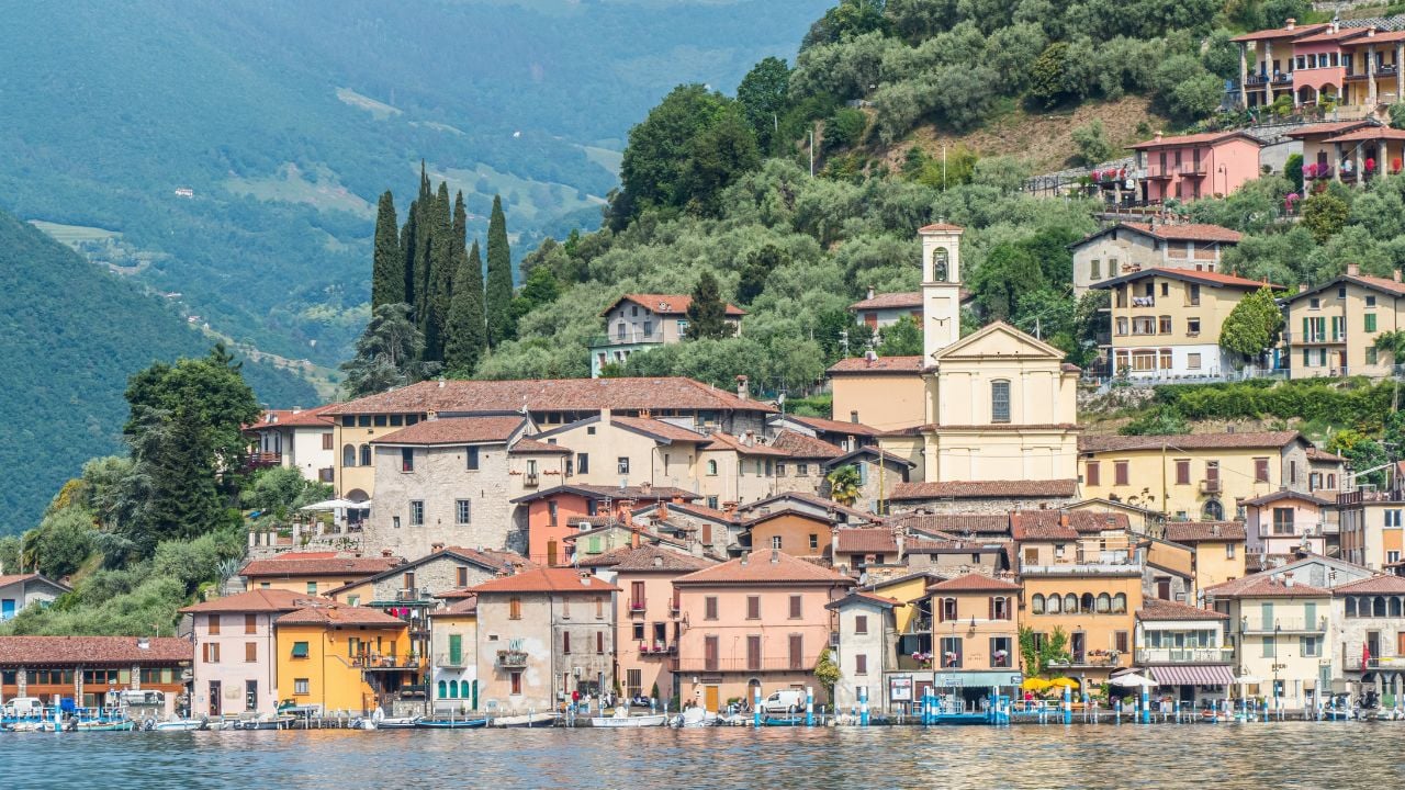 Monte Isola, Italy - 05-06-2022: Landscape of the lakeside of Peshiera Maraglio in Monte Isola with beautiful colored houses reflecting in the water