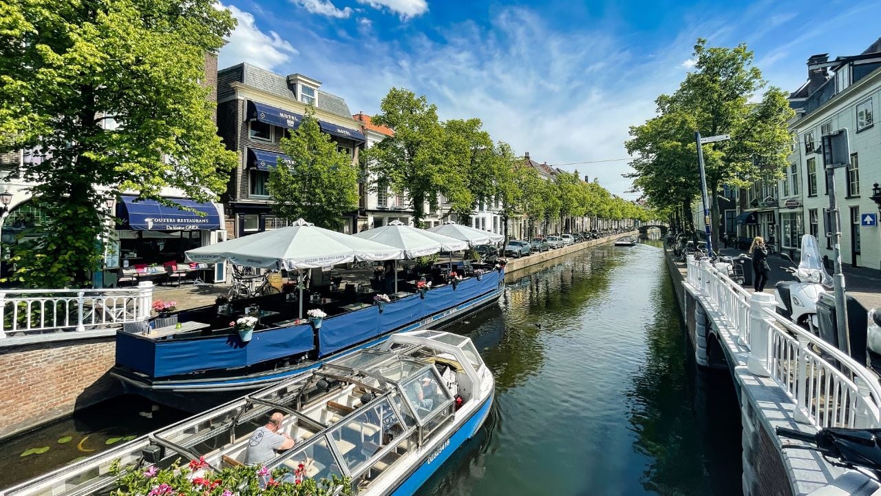 delft, netherlands - june 03 2022: tourist on bridge in historic dutch city with canal