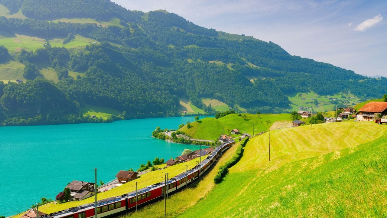 Panoramic train passing meadows, lake water, and mountains near Lungern, Switzerland