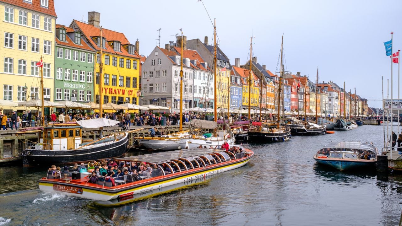 Nyhavn canal in Copenhagen, Denmark, with colorful facades, boats, and visitors