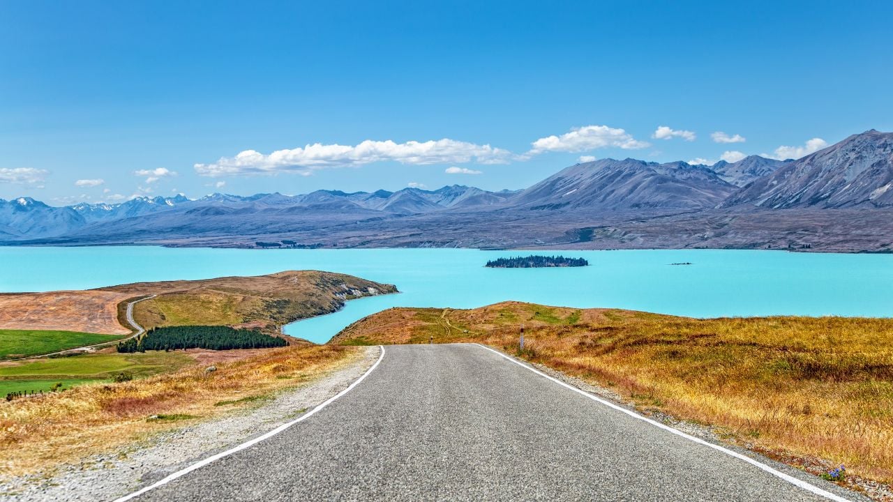 Lake Tekapo in Canterbury, New Zealand, with blue water, Motuariki Island, and mountain ranges in the distance